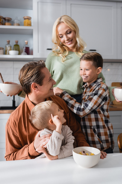 happy family looking at mother during breakfast in kitchen - Φωτογραφία, εικόνα