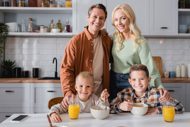 happy family looking at camera during breakfast in kitchen - Φωτογραφία, εικόνα