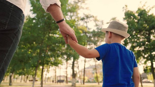 Dad, child, son are walking together in the park, holding hands. Dreams, happy family, childhood. Happy family walks down the street, kid, boy, father outdoors. Childrens dreams, family values - Photo, Image