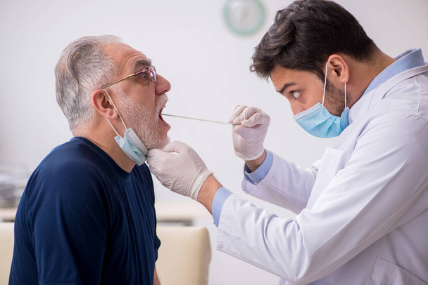 Old male patient visiting young male doctor otorhinolaryngologis - Photo, Image