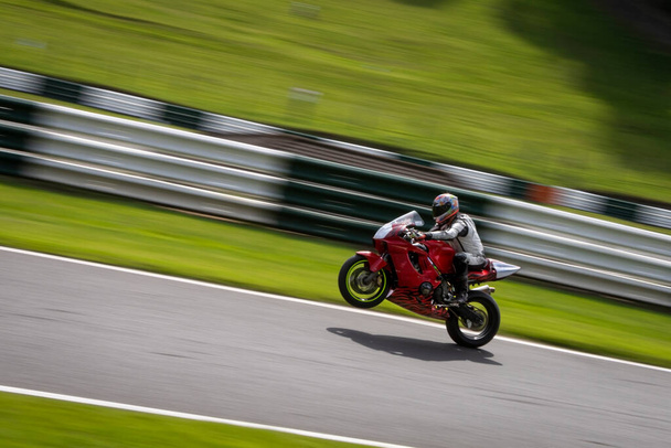 Una toma panorámica de una moto de carreras mientras circula una pista. - Foto, Imagen