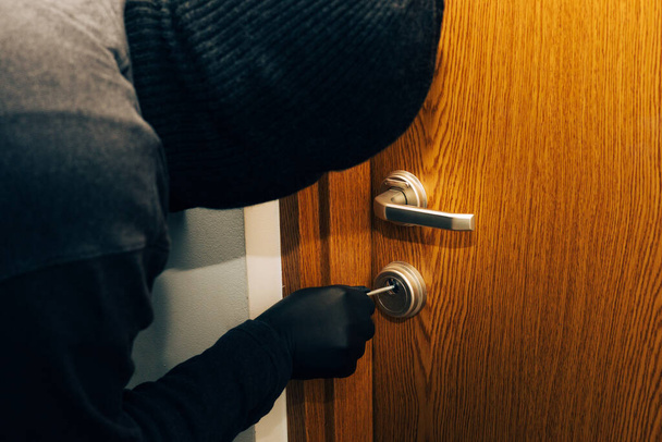 een man in een zwarte bivakmuts en handschoenen breekt in het appartement in  - Foto, afbeelding