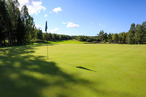 Flag shadow on a golf course with green grass - Fotó, kép