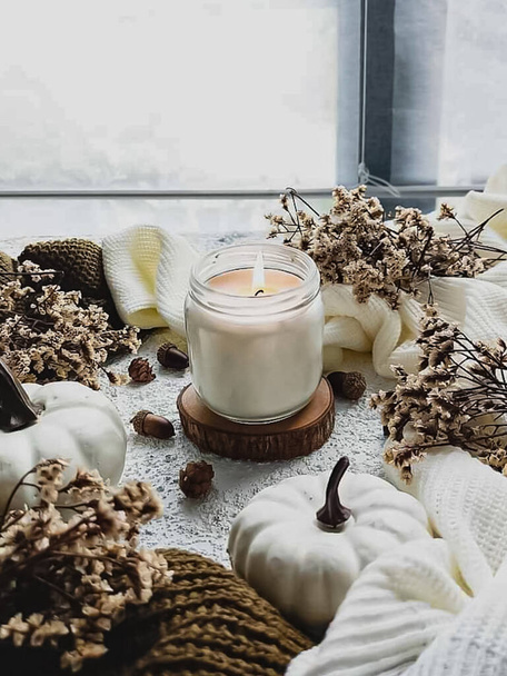 Осенний завтрак. свеча в стакане, эдельвейс цветок и белая тыква, вязание, белый стол фон.   - Фото, изображение