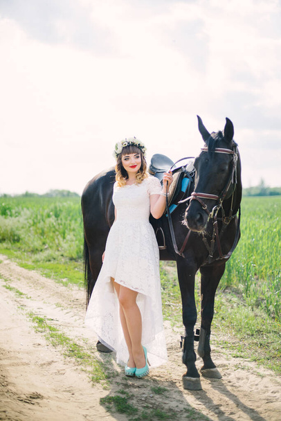 девушка с красными губами в белом платье рядом с черной лошадью - Фото, изображение