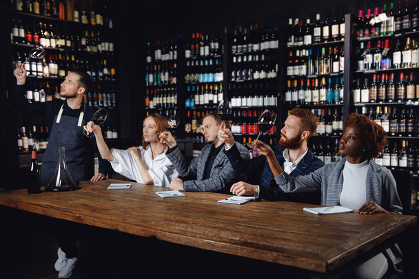 レストランのグラスから赤ワインを試飲し、ソムリエの専門家会議でメニューのアルコールカードを選ぶ - 写真・画像