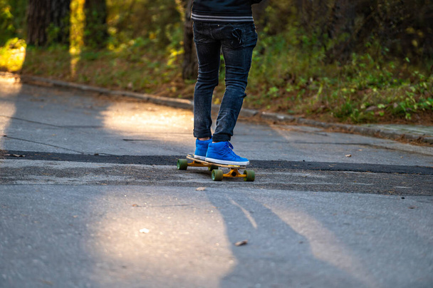 leisure activity, sportive lifestyle, man riding skateboard, feet and skateboard, closeup - Фото, изображение
