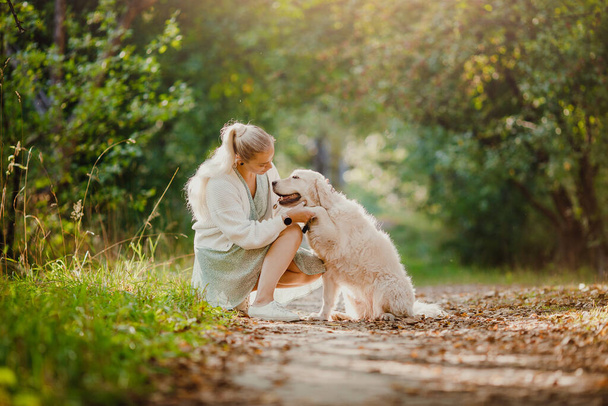 Concept Friendship girl and golden retriever. Pretty young woman with dog on background summer park - Fotoğraf, Görsel