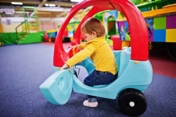 Cute baby girl rides on a plastic car in indoor play center. - Foto, immagini