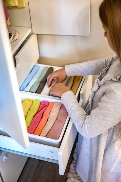 ロングヘアの10代の女の子は、マリー・コンドス法を使用しています。食器棚にアパレルを配置する - 写真・画像