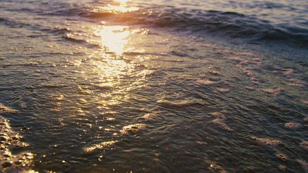 Спокойные морские волны, плескающиеся пляжным песком в солнечное утро. Золотой восход солнца - Фото, изображение