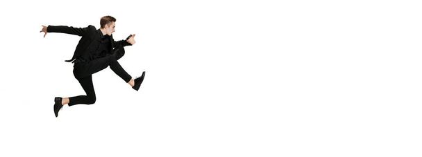 Молодий чоловік в чорному діловому костюмі танцює ізольовано на білому тлі. Мистецтво, рух, дія, гнучкість, концепція натхнення
. - Фото, зображення