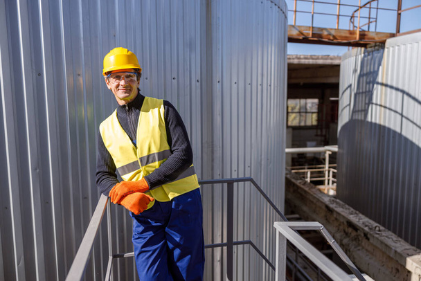 Mužský inženýr stojící v blízkosti kovového zásobníku v továrně - Fotografie, Obrázek