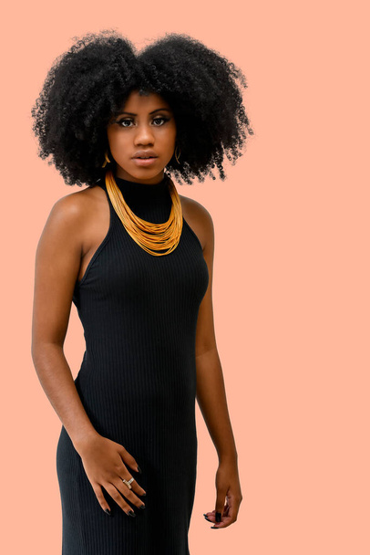 portrait of a beautiful black girl with an afro black power hairstyle isolated on a pink background - Foto, afbeelding