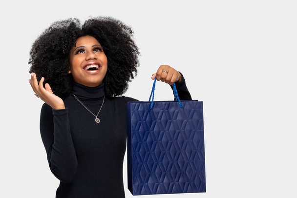 smiling girl holding shopping bags isolated on blue background - Foto, Imagem