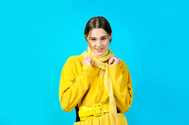 portrait of a teenage girl in yellow clothes. blue background - Фото, изображение
