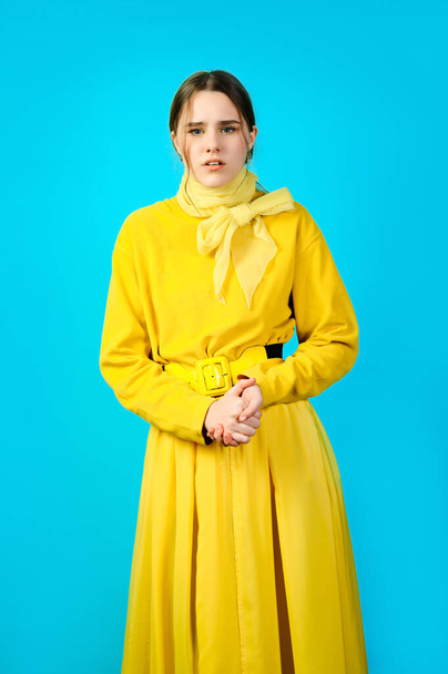 portrait of a teenage girl in yellow clothes. blue background - Foto, Imagen