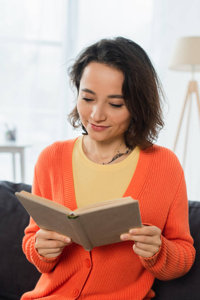 heureux et tatoué femme lecture livre à la maison - Photo, image