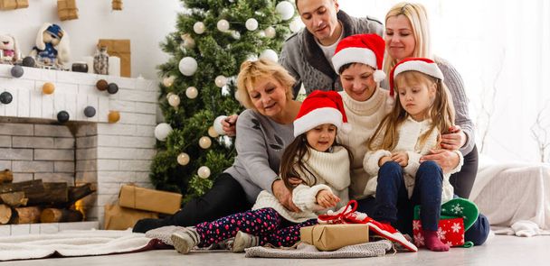 ευτυχισμένη οικογένεια κρατώντας χριστουγεννιάτικο δώρο και χαμογελώντας - Φωτογραφία, εικόνα