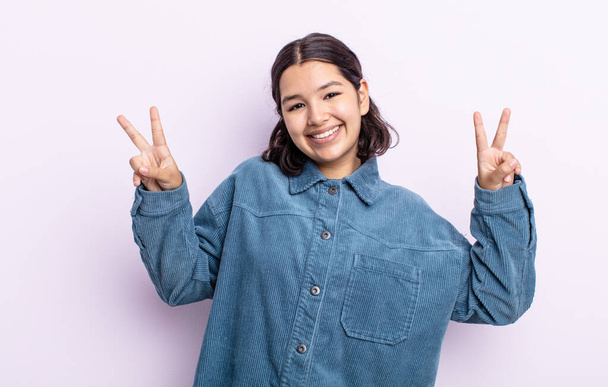 pretty teenager woman smiling and looking happy, friendly and satisfied, gesturing victory or peace with both hands - Фото, зображення