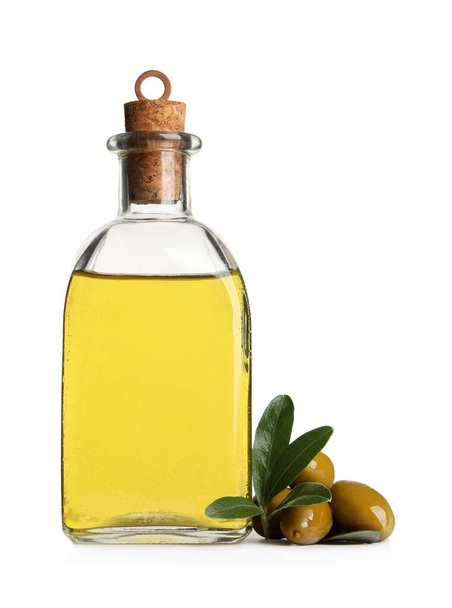 Glass bottle of oil, ripe olives and green leaves on white background - Zdjęcie, obraz