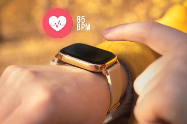 Inteligentní hodinky s ikonou srdeční frekvence, koncept zdravotní péče foto. Žena měření tepové frekvence venku - Fotografie, Obrázek