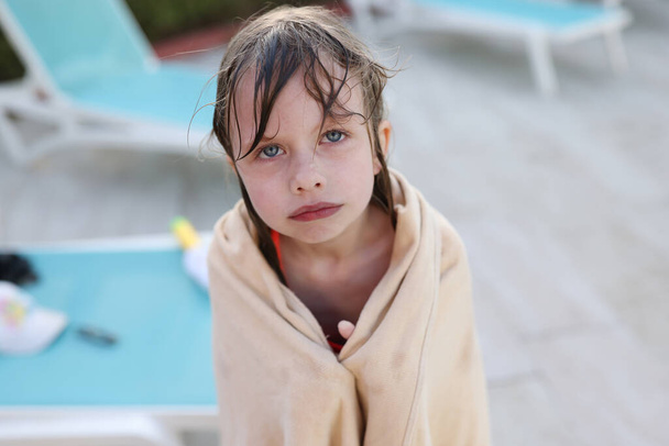 Маленька заморожена дівчинка в рушнику стоїть біля басейну
 - Фото, зображення