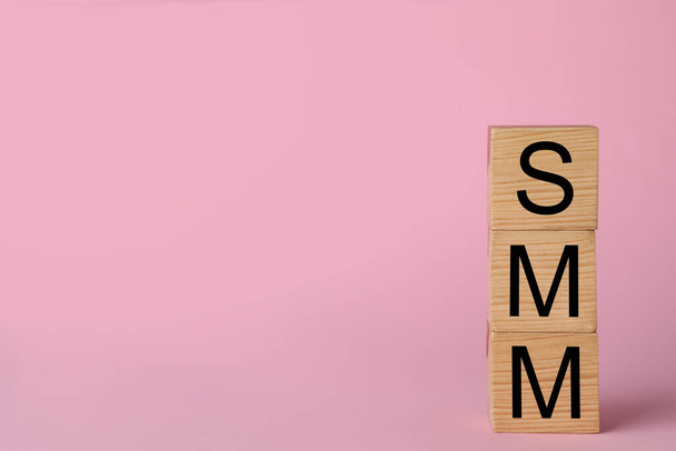 Wooden cubes with abbreviation SMM (Social media marketing) on pink background. Space for text - Fotó, kép