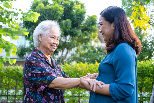 Asiatische Seniorin mit Pflegerin spaziert glücklich im Naturpark. - Foto, Bild