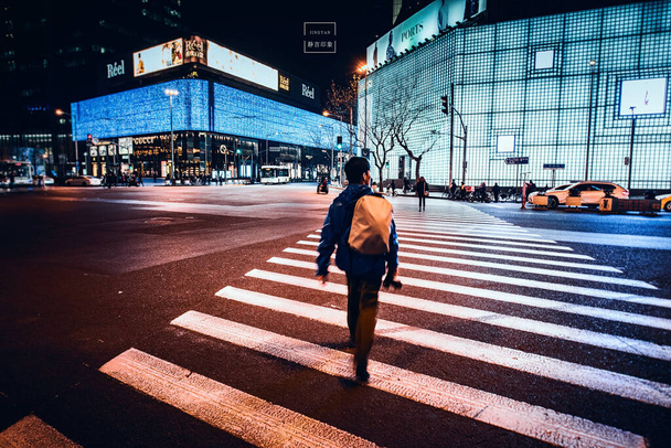 a man walks along the street with a backpack and a lantern - Zdjęcie, obraz