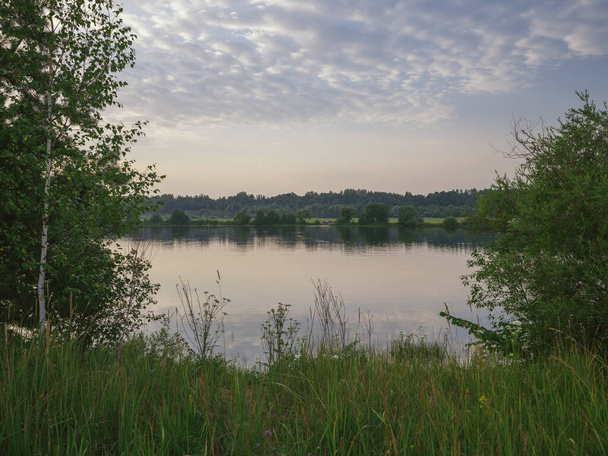 nebliger Morgen am See mit ruhigem Wasser, Nebel und Spiegelungen von Bäumen in Spiegeloberfläche. ruhige Sommerfarben - Foto, Bild