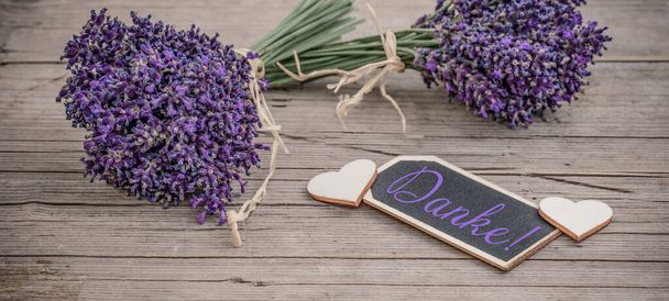 Gros plan de bouguet de lavendula violette fleurs de lavande herbes avec pendentif en bois avec le mot : "Merci", sur une vieille table rustique en bois, panorama de bannière de fond en bois - Photo, image