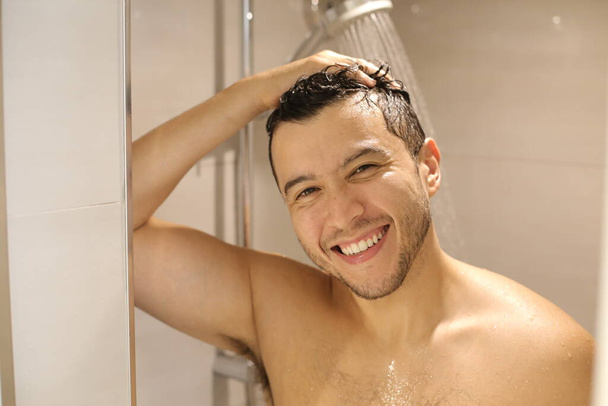 портрет красивого молодого мужчины без рубашки, принимающего душ - Фото, изображение