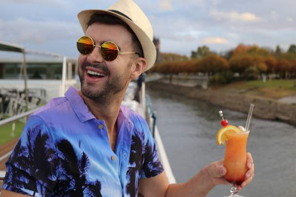 ritratto di bel giovane in cappello di paglia che tiene il bicchiere di cocktail sul fiume - Foto, immagini