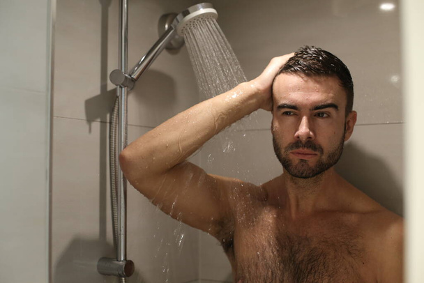 Porträt eines hübschen jungen Mannes ohne Hemd unter der Dusche - Foto, Bild