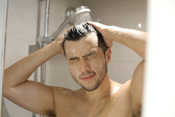 портрет красивого молодого мужчины без рубашки, принимающего душ - Фото, изображение