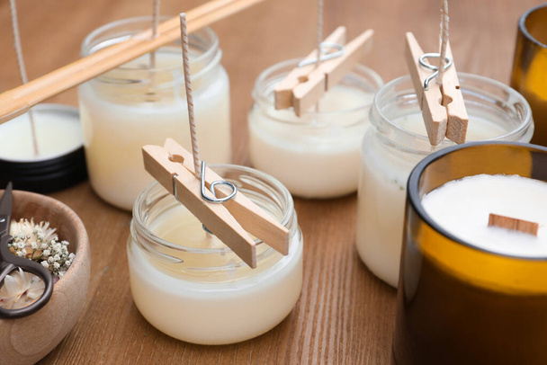Glass jars with wax on wooden table. Handmade candles - 写真・画像