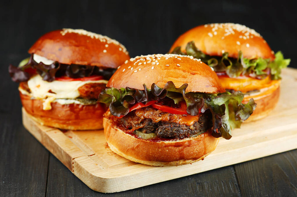 τρία μπέργκερ σε ξύλο. σετ burger σε ξύλινο κατάστρωμα closeup - Φωτογραφία, εικόνα