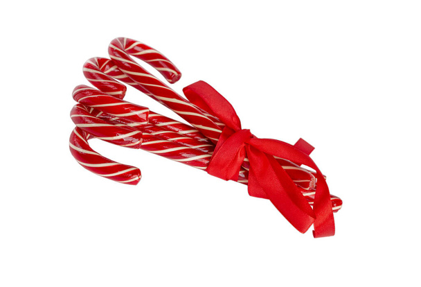 Bâtonnets de bonbons festifs attachés avec un ruban rouge. Isolé sur fond blanc. Concentration sélective. - Photo, image
