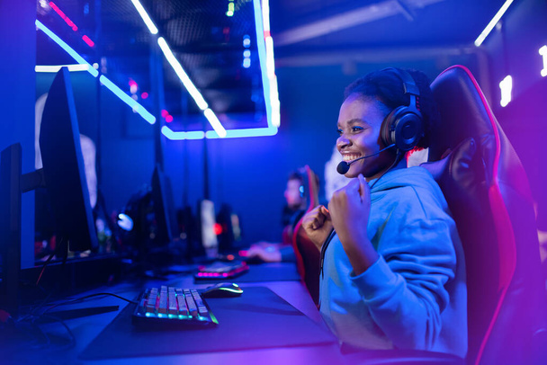 Professionele Streamer Afrikaanse jonge vrouw cyber gamer in neon kleur vervagen achtergrond - Foto, afbeelding