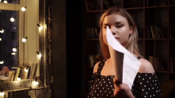 Young serious woman stands in room and waves by sheets of paper in her hand saying something - Footage, Video