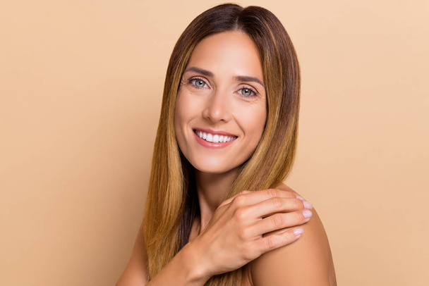 Portrait of attractive cheerful woman touching flawless smooth skin domestic lifting massage isolated over beige pastel color background. - Фото, изображение