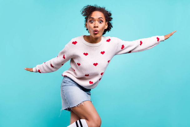 Photo of sweet impressed afro girl wear heart print pullover arms sides showing plane isolated blue color background. - Fotografie, Obrázek
