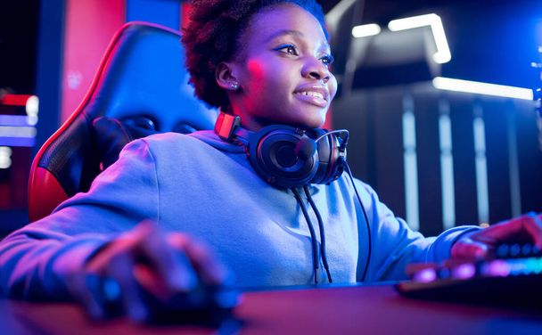 Portrait Gamer African American beautiful woman play online games computer, streamer neon room - Фото, изображение