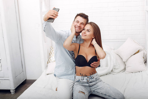 Couple sitting on a bed in a room and use the phone - Foto, afbeelding