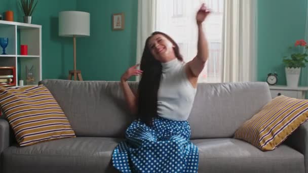 Mujer joven se sienta en el sofá y se divierte - Imágenes, Vídeo
