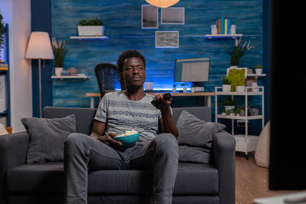 Африканский американец отдыхает на диване с помощью дистанционного управления - Фото, изображение