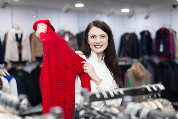 Woman choosing sweater at clothing store - 写真・画像