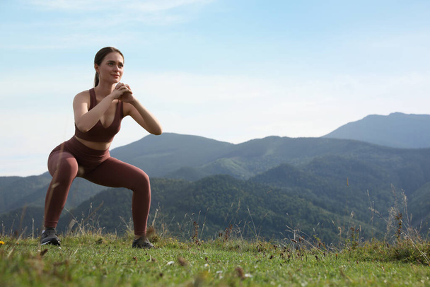 Young woman doing morning exercise in mountains, space for text - Fotoğraf, Görsel