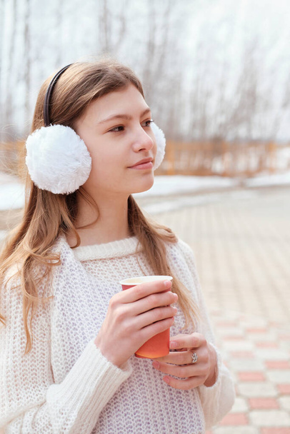 adolescente tenant une tasse de café à l'extérieur et regardant de côté. marche dans un parc à l'automne, tenue d'hiver. emporter café - Photo, image